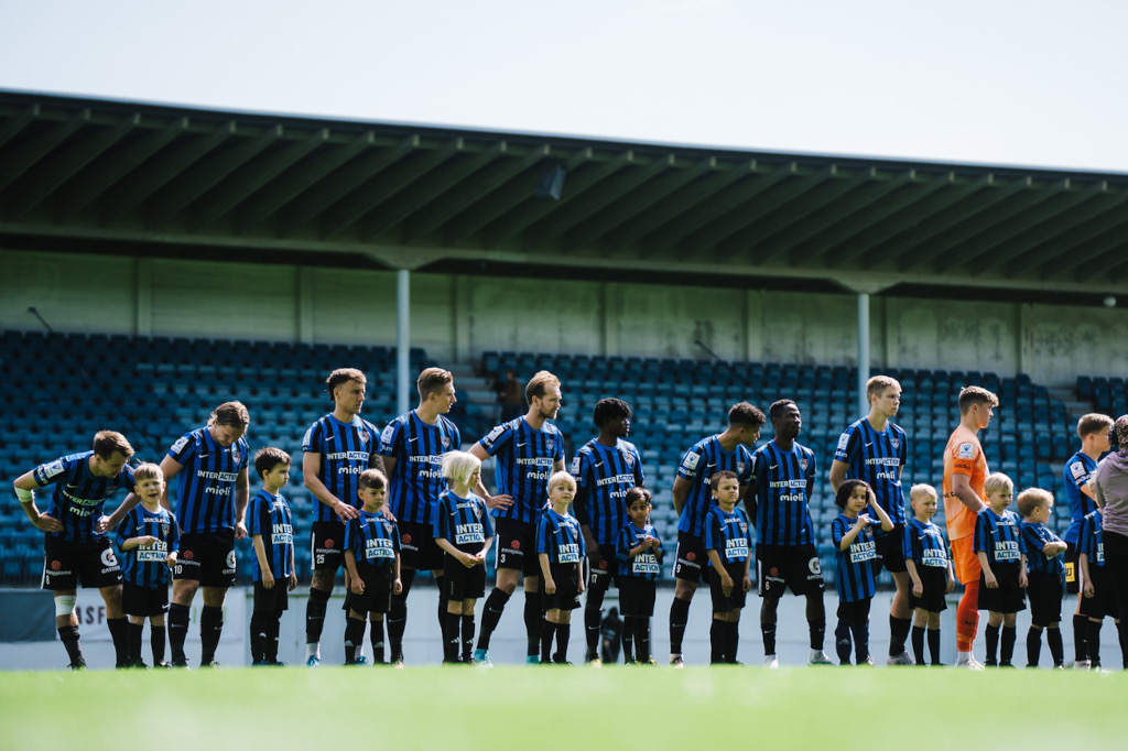 A soccer team stands in a line on a soccer field.